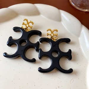 Vintage gold metal floral earrings with black resin pendants on a white lace plate