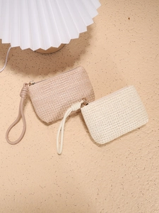 Woven straw coin purses in beige and cream with wrist straps on a textured background
