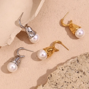 Detailed view of hammered gold and silver teardrop earrings with large round white pearls