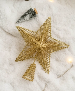 Detail of gold glitter star tree topper with hollow design and spiral base on snow
