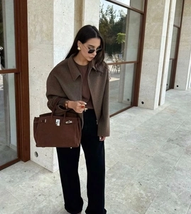 Close-up of brown suede zipper jacket and leather handbag on a street fashion model