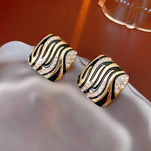 Details von Vintage-Ohrringen in Gold mit schwarzer Zebra-Emaille und Kristallen