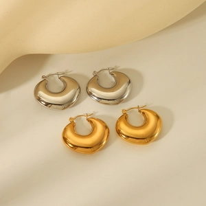 Set of thick hollow hoop earrings in polished gold and silver finishes on beige surface
