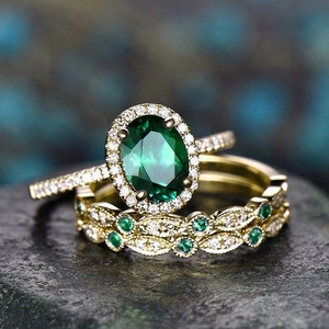 Macro detail of luxury gold rings set with oval emerald green gemstone and white diamonds
