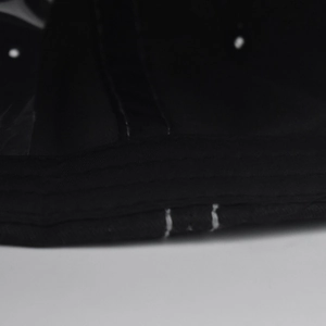 Macro shot of double stitching detail on black cotton washed baseball cap fabric