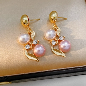 Vue macro de boucles d'oreilles feuille d'or avec perles et strass sur fond satin