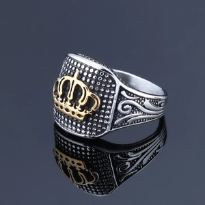 Vintage stainless steel crown ring in silver and gold finish on a black mirror surface