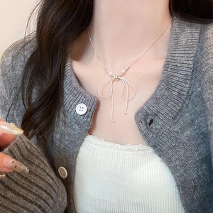 Detail of silver bow pendant necklace with pearls on a fine snake chain for women