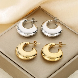 Vue macro de boucles d'oreilles créoles épaisses en C aux finitions or et argent