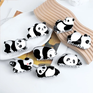 Set of cute panda hair claws in various poses on a white ceramic and wood tray