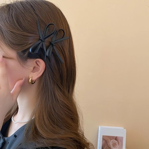 Close-up of black faux leather bow hair clips worn on side hair with y2k style