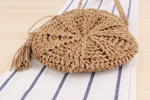 Detail of round straw shoulder bag with woven texture and long tassel fringe decoration