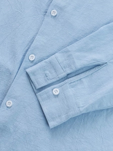 Detailed view of light blue linen shirt cuff and texture with white buttons