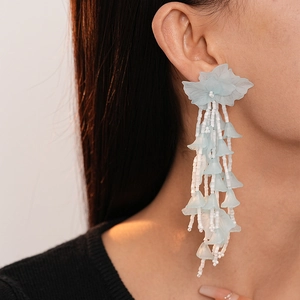 Detailed view of light blue acrylic leaf earrings with elegant white beaded tassels