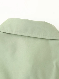 Close-up of the light green woven fabric neckline showing neat stitching and fine texture