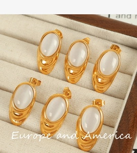 Detail view of 18k gold plated titanium steel earrings with white opal shell insets