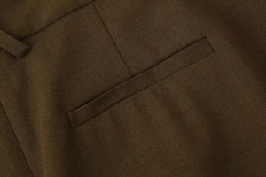 Vue macro détaillée de la poche latérale et de la texture en sergé du pantalon café foncé