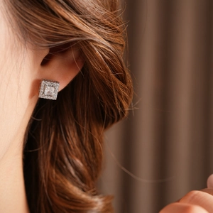 Close-up of a silver square zircon stud earring worn by a model with a radiant finish