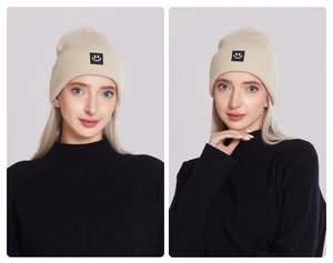 Detail of cream knit beanie featuring a minimalist black square smiley face patch