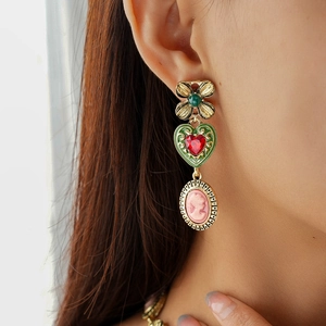 Detail of vintage gold earrings with cameo portrait, heart gem and floral motifs