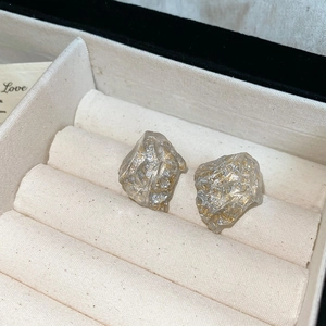 Detailed macro view of irregular resin earrings with gold and silver metallic texture