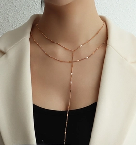 Close-up of double-layer rose gold Y-shaped necklace with geometric sequins on model
