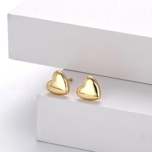 Macro detail of gold heart earrings with premium polished mirror finish on a white stand