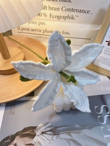 Close-up of handmade crochet white lily flower with detailed green pistil and petals