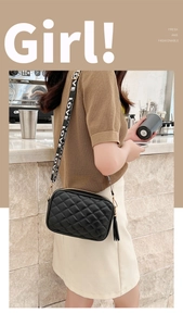 Close-up of black quilted camera bag with fringe tassel and LOVE print woven shoulder strap
