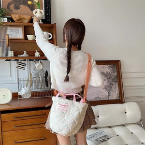 Détail du sac à bandoulière matelassé blanc avec fleurs bleues et anses roses