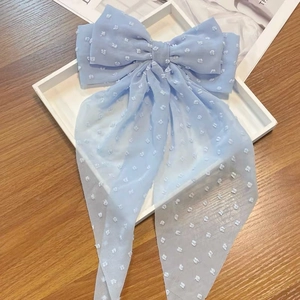 Close-up of a light blue chiffon bow hair clip with white Swiss dots and long ribbons