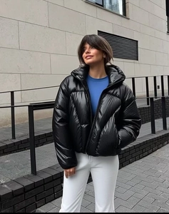 Detail of glossy black puffer jacket with stand collar and zipper on an outdoor model