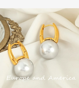 Close-up of elegant gold pearl drop earrings on white silk fabric background