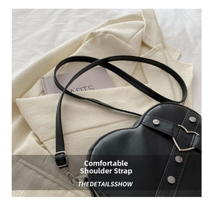 Détail du sac bandoulière noir en forme de cœur avec clous et boucle en métal