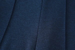 Vue macro du tissu sergé bleu marine avec détails plissés et coutures professionnelles