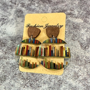 Detail of bookshelf printed acrylic earrings with wood geometric tops and classic book titles