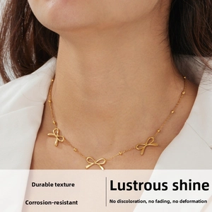 Detail of gold-plated bead chain necklace with hollow bow pendants on a model