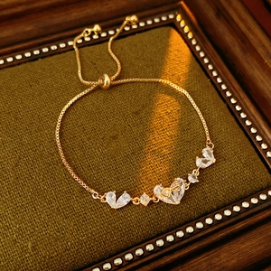 Detail of 18K gold heart bracelet with zircons on dark green velvet background