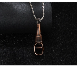 Détail macro du pendentif pipe en métal bronze avec chaîne argentée sur fond noir