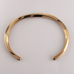 Detailed view of polished golden twisted Mobius open bangle with mirror finish