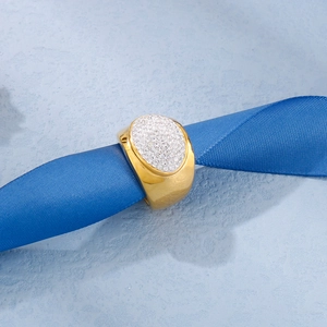 Macro view of wide gold-plated ring with full pavé crystal inlay on blue ribbon