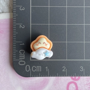 Mini yellow star and white cloud resin charm with size measurement on a grid mat