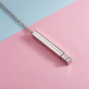 Macro detail of a silver rectangular titanium steel necklace on a blue and pink backdrop