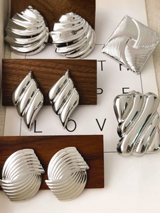 Detailed view of silver metallic geometric earrings on wood texture and card