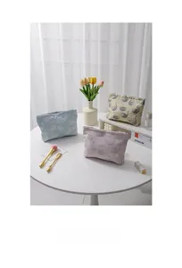 Swan jacquard toiletry bags in blue, purple, and khaki on a white table