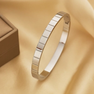 Dettaglio del bracciale geometrico in argento su sfondo di lussuosa seta dorata