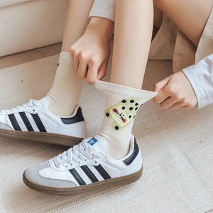 Detail shot of cream crew socks featuring a cute leopard cat cartoon patch and cotton texture