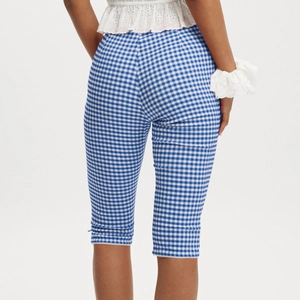 Detail view of blue plaid cropped pants with elegant white lace trim at the hem
