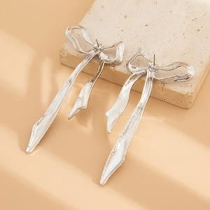 Dettaglio di orecchini a fiocco con nappe in metallo argento su espositore in pietra