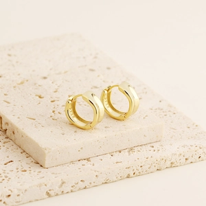 Close-up of gold-plated S925 sterling silver hoop earrings on a stone slab